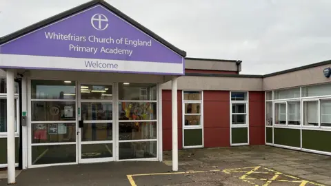 Exterior shot of Whitefriars Primary Academy. The school reception area has a purple school sign above it. 