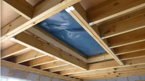 HSE A hole in the ceiling covered by blue tarpaulin.