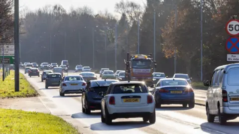 Stockport Council There are a number of cars and vans on this section of the A34 in Stockport, which is a straight dual carriageway. 