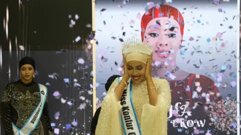 Shukri Mohamed Abdi A woman covers her ears and smiles as confetti is scattered near her