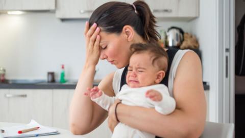 Stressed mother with child at kitchen table