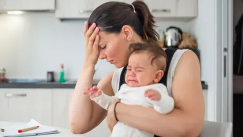 Stressed mother with child at kitchen table