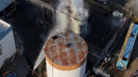 Reuters A drone picture shows water being sprayed on a tank as a chemical incident involving a failing tank of flammable liquid called methyl methacrylate, used in the aerospace industry, has forced an evacuation in the surrounding area in Garden Grove, California.