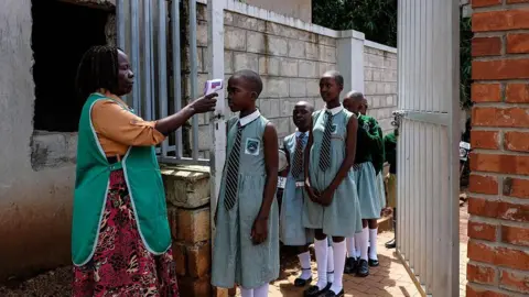 Getty Images A school nurse checks pupils' temperatures before they enter school 