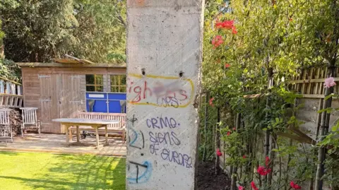 Steven Thorpe A large concrete chunk of wall with graffiti sitting on a lawn