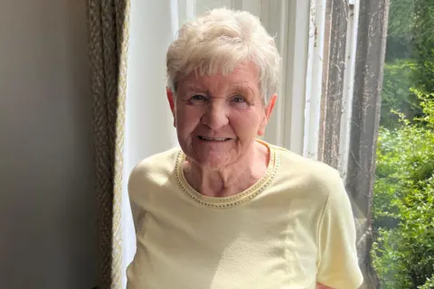 A woman with short light hair in a yellow top.