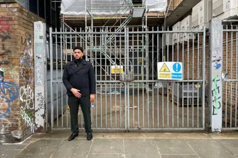 Dimitri Moses standing in front of the metal gate where he was Tasered by police