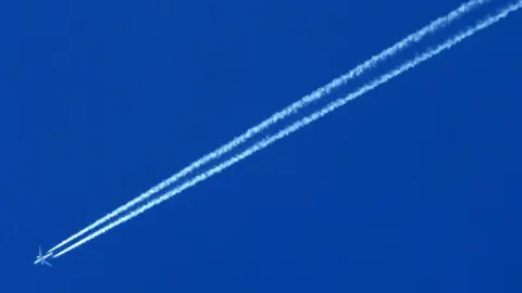 PA Media An airplane trailed by a contrail