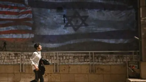 A man walks past a mural of an Israeli flag