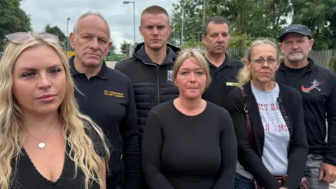 Seven business owners in a huddle, all wearing black standing in front of a tip with angry faces.