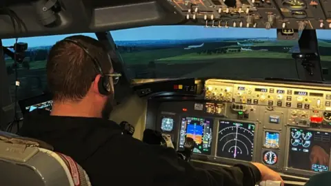 Image shoiwng the cockpit in the flight simulator. A man can be seen controlling it.