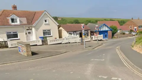 Houses and a cafe in Staithes, North Yorkshire, on a sunny day. A cafe has bunting across its entrance.