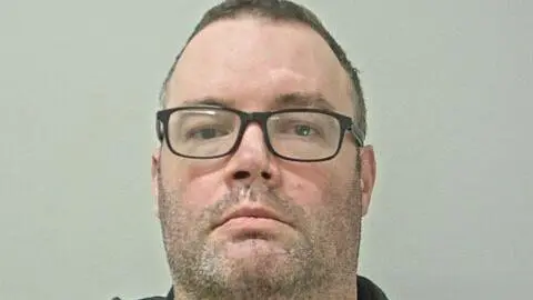Thomas Freret has dark-framed glasses, stubble and short dark hair.
