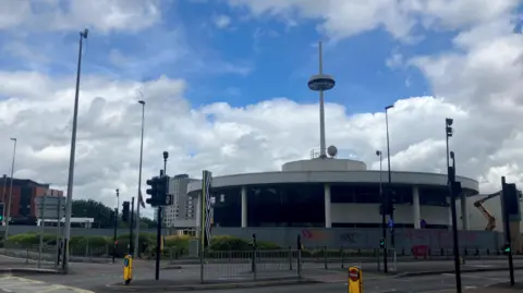 Photograph of the former Renault garage on Trinity Way in central Salford. The image shows a derelict car dealership, traffic lights and an empty road.