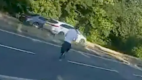 A man is running across a road away from police