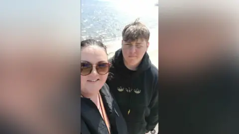 Marrissa Mullans has sunglasses, tied back brown hair and a black top. Her teenage Alfie is photographed with light brown hair and is wearing a black hoodie.
