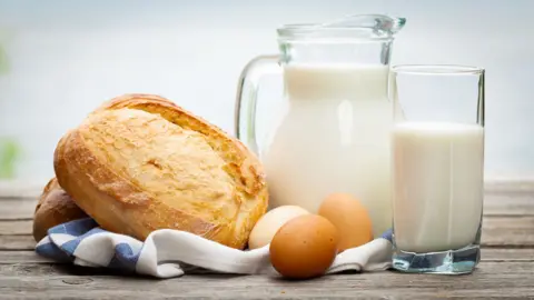 Bread, eggs and a jug and glass of milk on a table