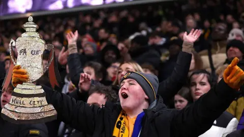 Getty Images A young Hull City fan holding a mock FA Cup trophy made with silver foil, bearing the club's name.