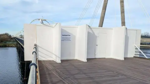 Kaleigh Watterson/BBC The end of the pier closed off white large white boarding and a temporary white sign which says Southport Pier in black writing