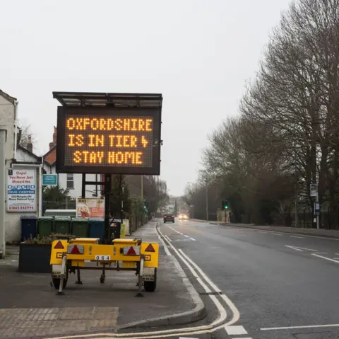 Wendy Aldiss An image of a sign instructing people to stay at home next to a main road