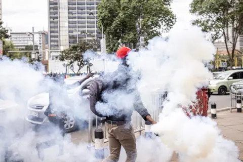 AFP A man holds a tear gas canister thrown by Kenyan police officers during a protest against police brutality and harassment, especially against the poor, in Nairobi on July 7, 2021.