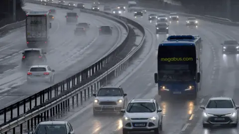 Generic image of cars, double-decker coach and lorry driving through water spray on the motorway