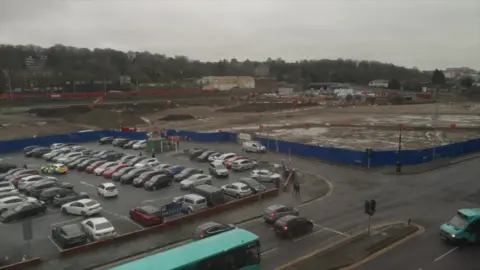 DJ McLaren/BBC A view from above of the construction site at Power Court, close to a busy car park.