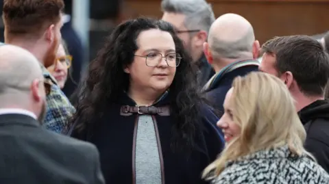 PA Media Storrie wearing glasses and a achromatic  cape with agelong  curly hairsbreadth  successful  teh mediate  of a crowd