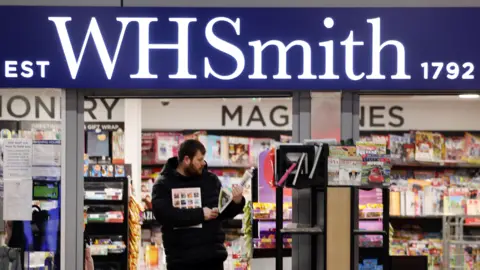 PA Media A man walks out of a WH Smith store, which displays a sign "established 1792"