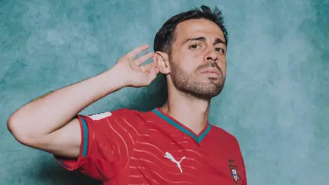 Bernado Silva cups his ear posing for a picture in a Portugal kit