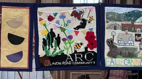 A wildlife scene on a banner which includes a bumble, plants and poppies.