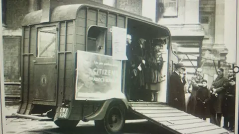 Citizens Advice A grainy black and white photo of an old horsebox with a sign outside saying 'Citizens Advice Bureau'.