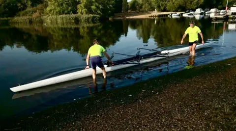 Two rowers putting a boat into the water