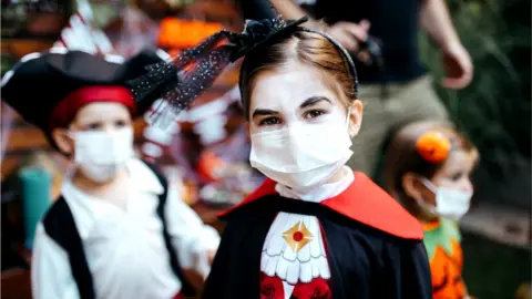 Getty Images Children dressed for Halloween in face coverings