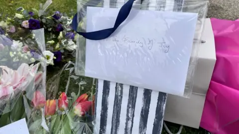 PA Media Flowers left outside a property in Pakefield, Suffolk, where 82-year-old Joy Middleditch died after masked robbers burst into her home and knocked her to the ground.