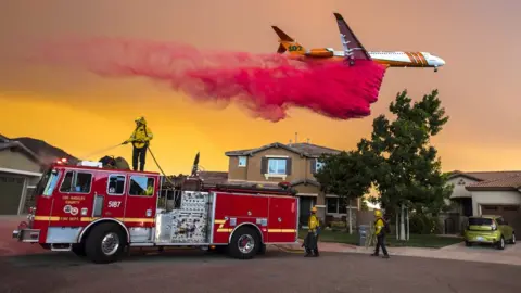 Getty Images A plane drops fire retardant behind homes along McVicker Canyon Park Road in Lake Elsinore in the US