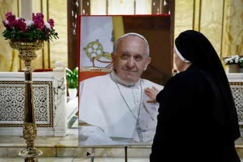 A nun touches a picture of Pope Francis
