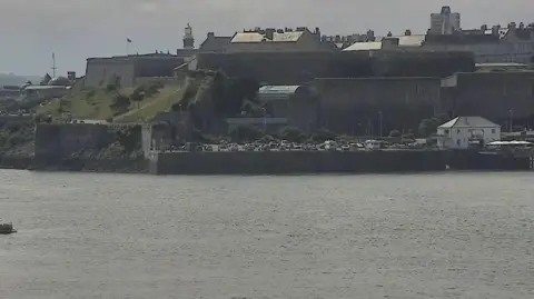 A CCTV picture of the harbour showing boats water and land in the background. The two swimmers in the water are barely visible. 