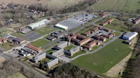 Alamy An aerial view of Catterick Garrison. Numerous large buildings are spread out among a series of grassy areas, with a car park and sports pitches also visible