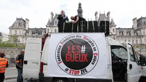Hans Lucas/AFP A man stands on top of a white van bearing the slogan Les #Gueux - the beggars