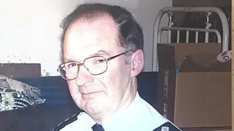 The Cook family  Roger Cook, wearing glasses and a black and white uniform, looks toward the camera