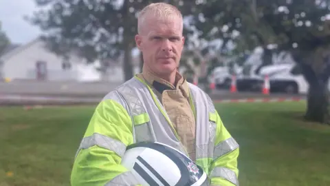 Paul Morrow wearing a NIFRS uniform, he is looking at the camera and he has light hair.  