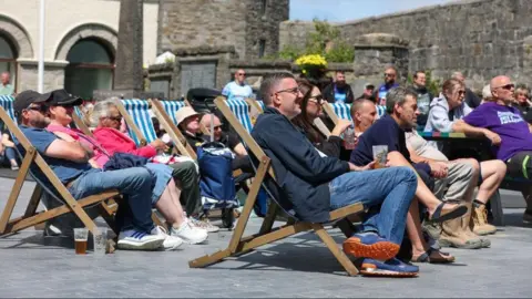 SOUTHERN 100 Fans sitting in blue and white striped deck chairs in Market Square.