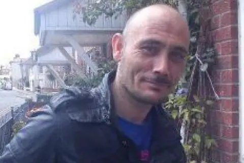 Contributed Ian Church standing outside a house. He is smiling at the camera and is wearing a leather-type jacket.