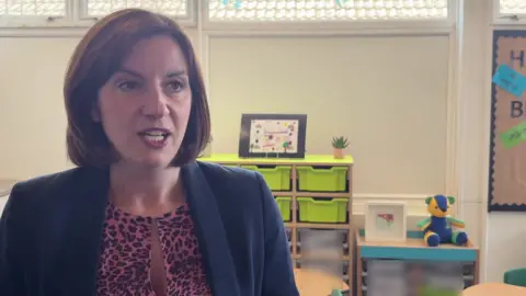 Bridget Phillipson MP, Education Secretary in a classroom. She is wearing a blazer and pink leopard print top.