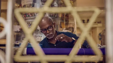 Thaha stitches a kippah in his shop