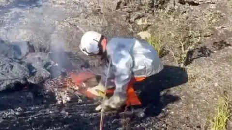 Scientist picks up lava with shovel