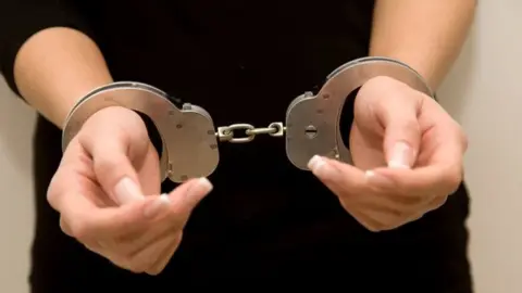 Getty Images Picture of woman's hands in handcuffs.