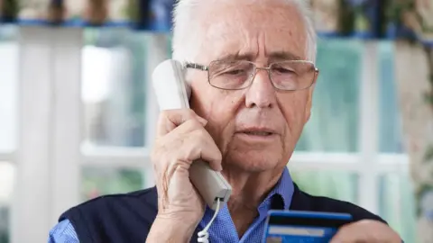 Getty Images older man on phone with credit card in hand