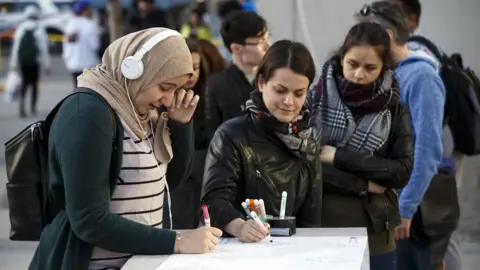 Getty Images Three women signing, with one wiping tears away from her eyes